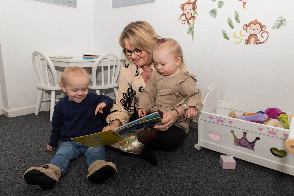 Krista Sønderup læser en bog med de børn hun passer i sin private børnepasning